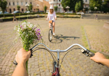 Man with flowers and woman in hat  riding on bicycles to each other. Close-up.の写真素材