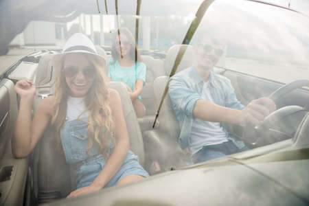Group of happy friends in sunglasses traveling on the cabriolet. Front view.の写真素材