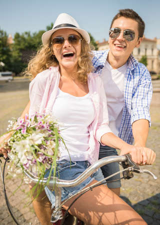 Portrait of couple in sunglasses riding on bicycle together on the city street.の写真素材