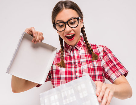Surprised girl in glasses opening present box on white background.