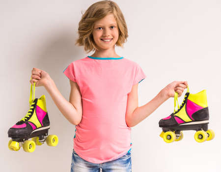 Portrait of smiling girl holding roller skates on white background.の写真素材