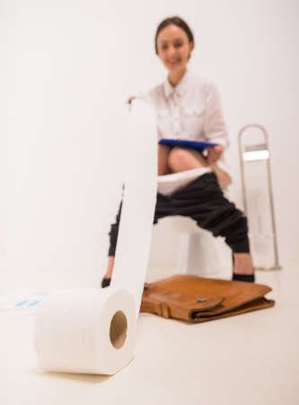 Young business woman using documents sitting in the toilet in the morning.の写真素材