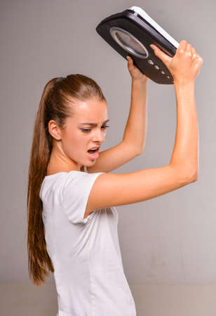 Frustrated woman with scale, on gray background.の写真素材
