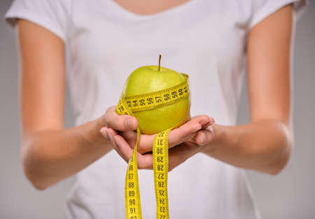 Young woman is holding apple and measure tape.  Healthy food concept.の写真素材