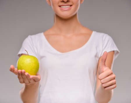 Close-up of young woman with green apple. Healthy food concept. Skin care and beauty. Vitamins and minerals.の写真素材