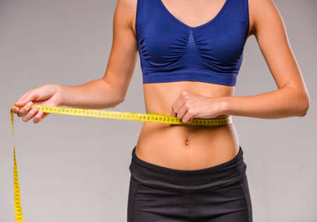 Young skinny woman is measuring her waist during diet.の写真素材