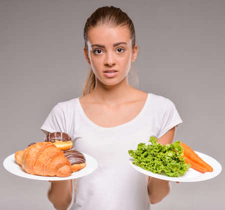Difficult choice between junk and healthy food. Vegetables or sweets.の写真素材