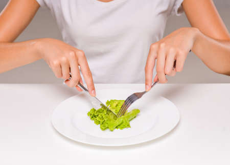 Healthy eating, vegetarian food, dieting. Young woman is eating a salad.の写真素材