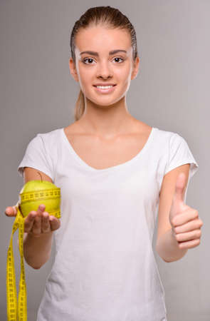 Young pretty woman is holding apple and measure tape.  Healthy food concept.の写真素材