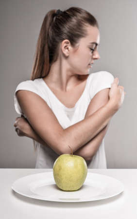 Young sadness woman with an apple. Concept of diet.の写真素材