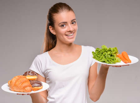 Difficult choice between junk and healthy food. Vegetables or sweets.の写真素材