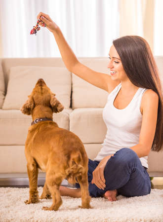 Happy woman is playing with a dog sitting on the floor at home.の写真素材