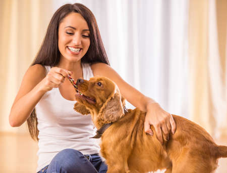 Happy woman is playing with a dog sitting on the floor at home.の写真素材