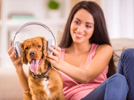Young woman and her dog with headphone is listening a music.の写真素材