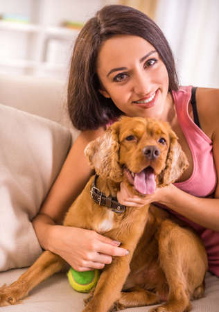 Young, attractive woman is playing with dog at home.の写真素材