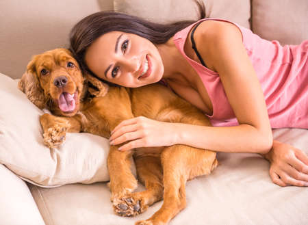 Young, attractive woman is playing with dog at home.の写真素材
