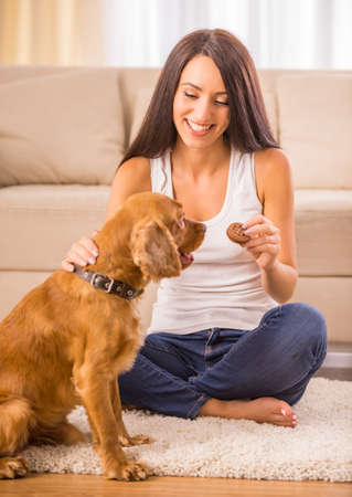 Happy woman is playing with a dog and feeding him.の写真素材