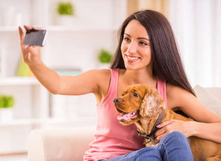 Young woman is making a picture with her cute dog pet.の写真素材