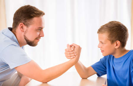 Little boy and his dad are competing in physical strength.の写真素材