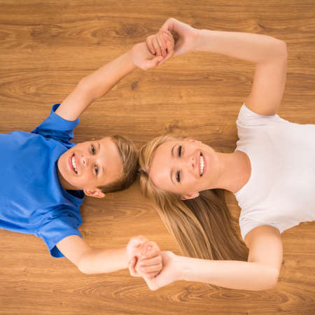 Top view of happy mother and son smiling to the camera, lying on the floor.の写真素材