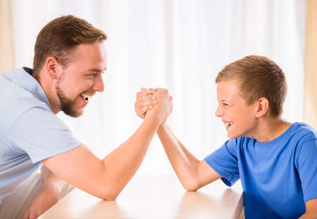 Little boy and his dad are competing in physical strength.の写真素材