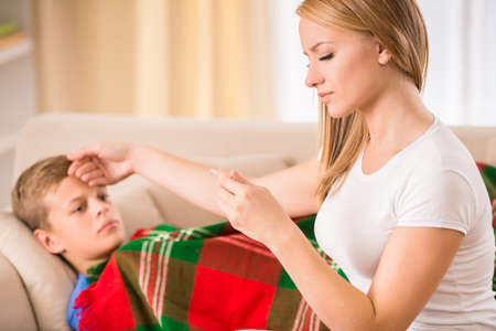 Mom checking the temperature of her ill son.の写真素材