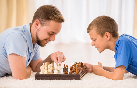 Father and son spend time together, are playing chess.の写真素材