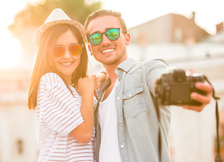 Young happy couple are taking selfie photo with photo camera.