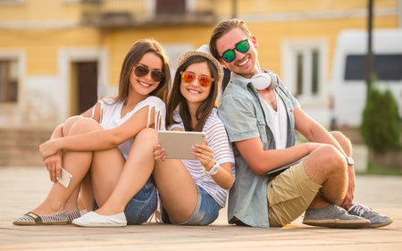 Friendship, leisure and people concept. Young people having a good time together, using digital...