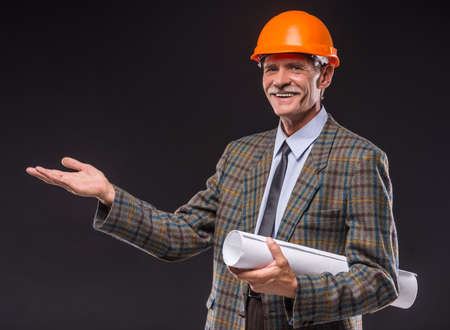 Senior man in suit and helmet  is holding draft.の写真素材