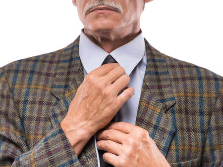 Senior man in blue shirt adjusting his necktie.の写真素材