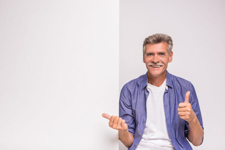 Happy senior man is holding blank placard on white background.の写真素材