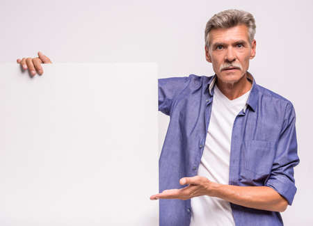 Happy senior man is holding blank placard on white background. Here can be your advertising.の写真素材