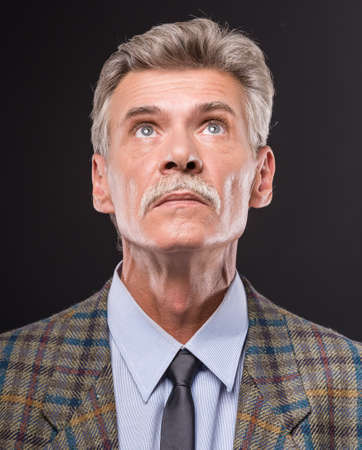 Close-up of senior man is looking up, on dark background.の写真素材