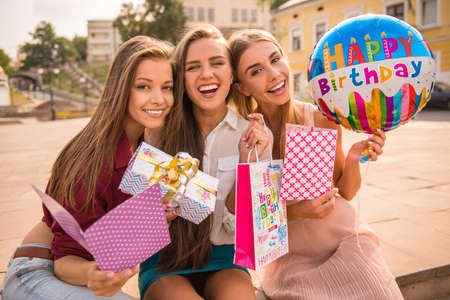 Three beautiful young women celebrating a birthday, outdoorsの写真素材