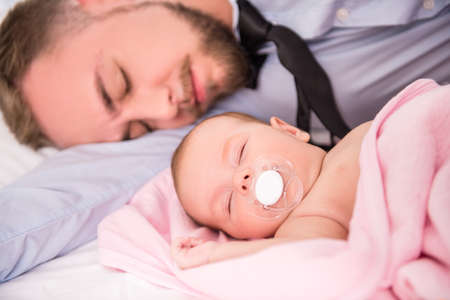 Portrait of young happy father with a baby at homeの写真素材