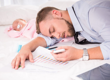 Portrait of young happy father with a baby at homeの写真素材