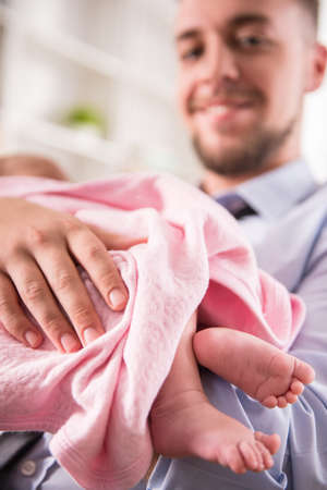 Portrait of young happy father with a baby at homeの写真素材