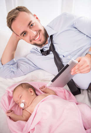 Portrait of young happy father with a baby at homeの写真素材