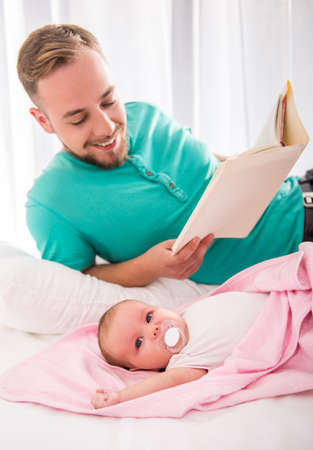 Portrait of young happy father with a baby at homeの写真素材