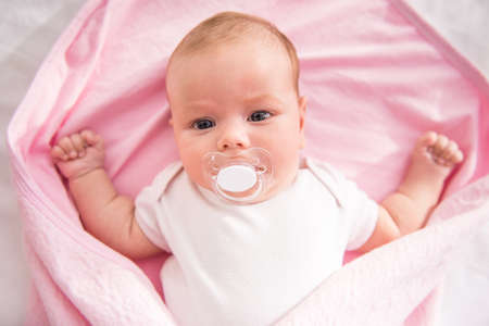 Portrait of a happy baby lying on the bed at homeの写真素材