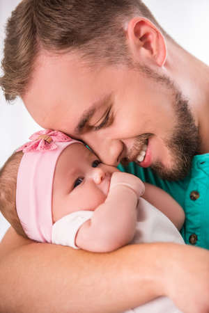 Portrait of young happy father with a baby at homeの写真素材