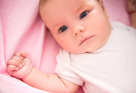 Portrait of a happy baby lying on the bed at homeの写真素材