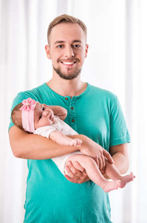 Portrait of young happy father with a baby at homeの写真素材