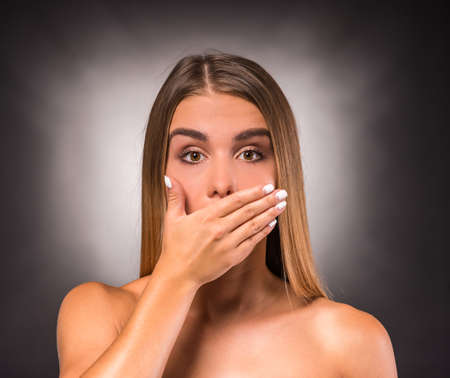 Portrait of a young, beautiful, emotional woman on a dark background. Studio shootの写真素材