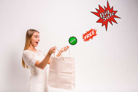 Portrait of a young, beautiful woman, holding a hand bag for shopping, gray background. Studio shootの写真素材