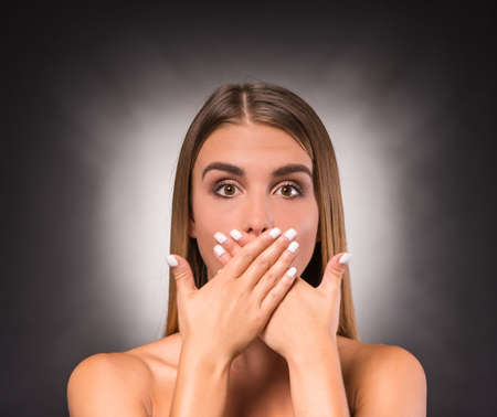 Portrait of a young, beautiful, emotional woman on a dark background. Studio shootの写真素材