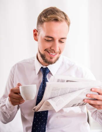 Young businessman drinking coffee and reading the newspaperの写真素材