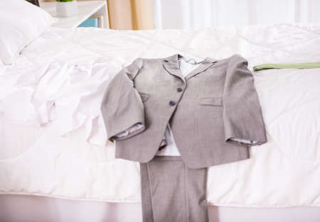 Business suit, lying on a bed in a bedroom at homeの写真素材