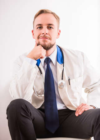 Portrait of tired young doctor in a white coat on a white backgroundの写真素材